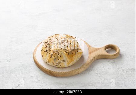 In Blätterteigkäse gebacken, mit Samen auf einem Holzbrett auf grauem, strukturiertem Hintergrund bestreut Stockfoto