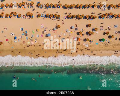 Drohnenantenne von Sonnenschirmen am Strand. Sommerurlaub im Meer Stockfoto