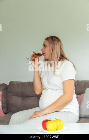 Eine schwangere Frau trinkt Wein in einem Glas. Selektiver Fokus. Essen. Stockfoto