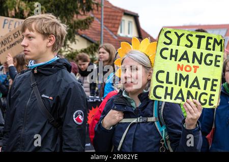 07. Mai 2023, Sachsen, Schleife: „Systemwechsel nicht Klimawandel“ steht auf einem Poster, das ein Teilnehmer bei einer Rallye in Schleife, Sachsen, bei sich trägt. Eine Allianz von Umweltverbänden, Klimaverbänden und lokalen Initiativen habe eine Demonstration im Tagebau Nochten in Lusatia gefordert. Unter anderem Fridays for Future, Greenpeace, Campact, BUND Sachsen, GRÜNE LIGA, Alle Dörfer bleiben, serbski sejm nehmen Teil. Das Bündnis fordert einen früheren Kohleabbau in Ostdeutschland als 2038 und sagt, dass der Strukturwandel den Menschen in der Region nachhaltige Arbeitsplätze bieten muss Stockfoto