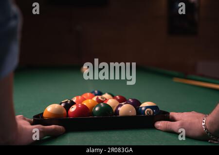 Nahaufnahme von männlichen Händen, die Billardkugeln auf den Billardtisch legen. Amerikanisches Billard-Konzept Stockfoto