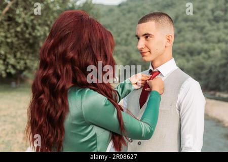 Junge Frau, die eine Krawatte für ihr Abschlussball-Date repariert Stockfoto