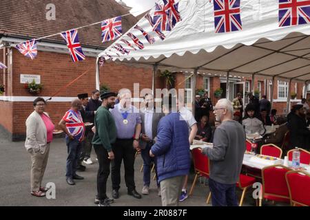 Croydon, Greater London, Großbritannien. 7. Mai 2023. Die Krönungsfeier von König Charles III. Geht weiter mit vielfältigen Mittagessen, Partys und Versammlungen im ganzen Land - hier in der Baitus Subhan Moschee in Croydon. Bilder sind Gäste, die den örtlichen Executive Mayor Jason Perry (hellblaues Hemd) umgeben. Kredit: Motofoto/Alamy Live News Stockfoto