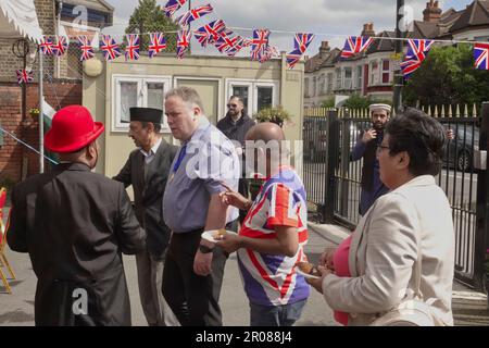 Croydon, Greater London, Großbritannien. 7. Mai 2023. Die Krönungsfeier von König Charles III. Geht weiter mit vielfältigen Mittagessen, Partys und Versammlungen im ganzen Land - hier in der Baitus Subhan Moschee in Croydon. Bilder sind Gäste, die den örtlichen Executive Mayor Jason Perry (hellblaues Hemd) umgeben. Kredit: Motofoto/Alamy Live News Stockfoto