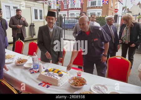 Croydon, Greater London, Großbritannien. 7. Mai 2023. Die Krönungsfeier von König Charles III. Geht weiter mit vielfältigen Mittagessen, Partys und Versammlungen im ganzen Land - hier in der Baitus Subhan Moschee in Croydon. Abgebildet sind einheimische Würdenträger, die den „königlichen“ Kuchen anschneiden. Kredit: Motofoto/Alamy Live News Stockfoto