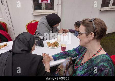 Croydon, Greater London, Großbritannien. 7. Mai 2023. Die Krönungsfeier von König Charles III. Geht weiter mit vielfältigen Mittagessen, Partys und Versammlungen im ganzen Land - hier in der Baitus Subhan Moschee in Croydon. Auf der Abbildung führen Jugendliche das traditionelle indische Henna-Ritual für einige weibliche Gäste vor. Kredit: Motofoto/Alamy Live News Stockfoto