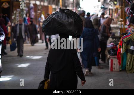 Eine Araberin trägt eine Tasche auf dem Kopf auf dem Straßenmarkt Stockfoto