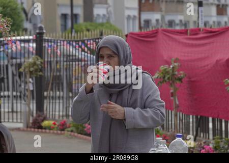 Croydon, Greater London, Großbritannien. 7. Mai 2023. Die Krönungsfeier von König Charles III. Geht weiter mit vielfältigen Mittagessen, Partys und Versammlungen im ganzen Land - hier in der Baitus Subhan Moschee in Croydon. Eine einheimische Frau trinkt aus einem Union Jack Cup Credit zur königlichen Krönung: Motofoto/Alamy Live News Stockfoto