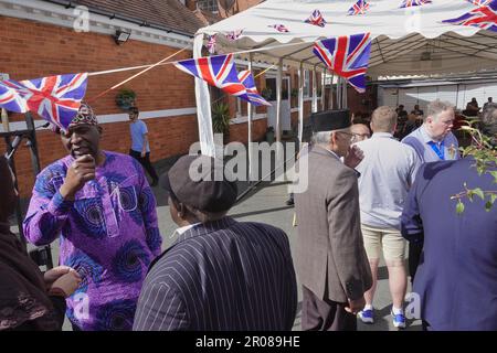 Croydon, Greater London, Großbritannien. 7. Mai 2023. Die Krönungsfeier von König Charles III. Geht weiter mit vielfältigen Mittagessen, Partys und Versammlungen im ganzen Land - hier in der Baitus Subhan Moschee in Croydon. Hier: Die männlichen Gäste unterhalten sich mit dem örtlichen Labour-Abgeordneten und dem Schattenminister im Innenministerium, Sarah Jones und dem geschäftsführenden Bürgermeister von Croydon, Jason Perry. Kredit: Motofoto/Alamy Live News Stockfoto