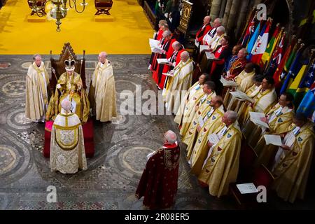 König Karl III., sitzt in St. Edwards Stuhl, auch bekannt als der Krönungsstuhl, nachdem er vom Erzbischof von Canterbury mit der Krone von St. Edward gekrönt wurde, dem Reverend Justin Welby, Und während seiner Krönungszeremonie in Westminster Abbey, London, das Zepter des Sovereign mit der Taube (in der linken Hand) und das Zepter des Sovereign mit Kreuz (in der rechten Hand) halten. Foto: Samstag, 6. Mai 2023. Stockfoto