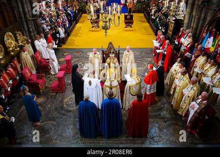 König Karl III., umgeben von Glaubensführern, während er auf dem Stuhl des Heiligen Edward saß, auch bekannt als Krönungsstuhl, trägt die Krone des Heiligen Edwards mit dem Zepter des Herrschers mit der Taube (in der linken Hand) und das Zepter des Herrschers mit Kreuz (in der rechten Hand), Während seiner Krönungszeremonie in Westminster Abbey, London. Foto: Samstag, 6. Mai 2023. Stockfoto