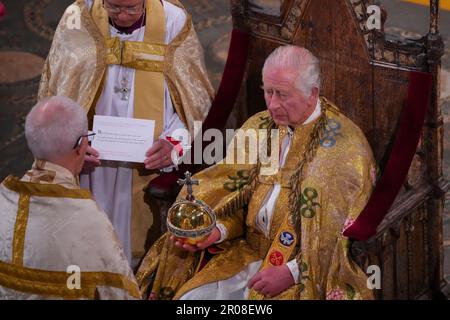 König Karl III. (Vorderes Zentrum) sitzt im St. Edward's Chair, auch bekannt als der Krönungsstuhl, und hält während seiner Krönungszeremonie in Westminster Abbey, London, den Orb des Herrschers. Foto: Samstag, 6. Mai 2023. Stockfoto