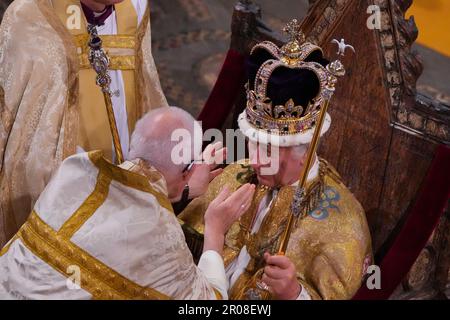 König Karl III., der in St. Edwards Stuhl sitzt, auch bekannt als der Krönungsstuhl, wird während seiner Krönungszeremonie in Westminster Abbey, London, vom Erzbischof von Canterbury, dem größten Reverend Justin Welby, mit der Krone von St. Edward gekrönt. Der König hält während seiner Krönungszeremonie in Westminster Abbey, London, das Zepter des Herrschers mit der Taube in seiner linken Hand und das Zepter des Herrschers mit Kreuz in seiner rechten Hand. Foto: Samstag, 6. Mai 2023. Stockfoto