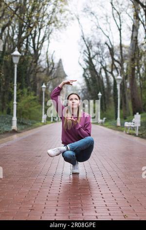 Junge, lässige Frau, die an Regentagen im Park tanzt. Stockfoto