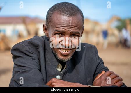 Ein alter Mann sitzt und lächelt auf einem Cemelmarkt in Hargeisa, Somaliland Stockfoto