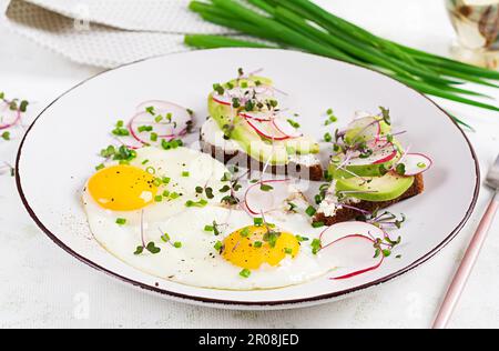 Spiegeleier und Sandwiches mit Avocado und Rettich für ein gesundes Frühstück. Stockfoto