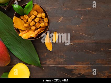 Von Mango getrocknete Scheiben und Kugeln in Schüssel auf Holzhintergrund. Draufsicht. Stockfoto