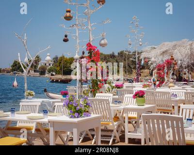 Bodrum Sommerreise in die Türkei. Tisch im Fischrestaurant der Ägäis in Gumusluk, Bodrum, Türkei. Restauranttische und -Stühle sind im Meer Stockfoto