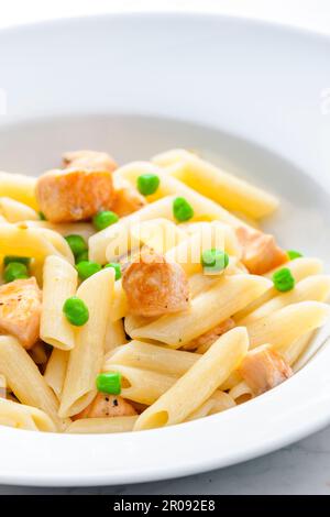 Pasta Penne mit Lachs und grünen Erbsen Stockfoto