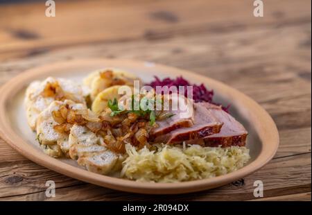 Geräuchertes Fleisch, serviert mit Rot- und Weißkohl und zwei Sorten Knödel Stockfoto