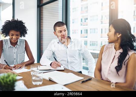 Lassen Sie uns weiter über unsere Strategien sprechen. Eine Gruppe von Kollegen, die ein Meeting in einem modernen Büro abhalten. Stockfoto