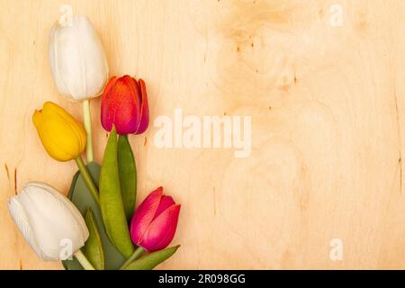 Tulpenblumen auf Holzhintergrund mit Kopierraum. Anmutige Tulpen bringen Freude auf die Grußkarte. Stockfoto