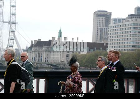 Die gut gepflegten Gäste für die Krönung von König Karl III. Kommen früh an der Lambeth Bridge an und begeben sich zu den Victoria Tower Gardens in London Stockfoto