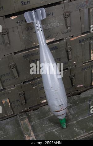 Sowjetische oder russische 120 mm Mörsergranate auf grüner Militärkiste. Text auf russisch - Art der Ammunition, Geschoss Kaliber, Geschoss Typ, Anzahl der Stücke Stockfoto