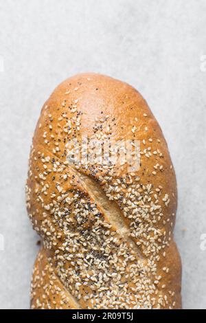 Ein Laib mit hausgemachtem Brot garniert mit Sesamsamen auf einer Marmorarbeitsfläche, Blick von oben auf Sesambrot, Sandwichbrot auf einem weißen Tablett Stockfoto