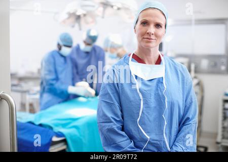 Von den Besten lernen. Porträt einer selbstbewussten, reifen Ärztin, die ihre Krankenhauskittel trägt und in einem Operationssaal steht. Stockfoto