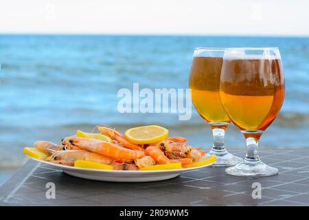 Kaltes Bier in Gläsern und Shrimps mit Zitrone am Strand Stockfoto