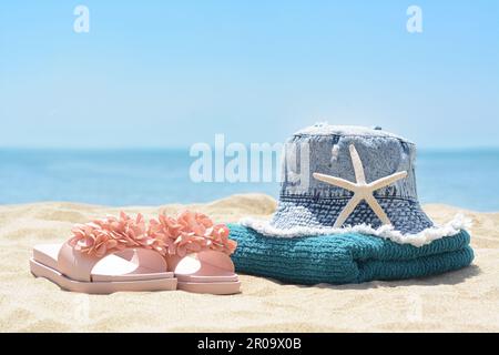 Stilvolles Strandzubehör auf Sand nahe am Meer Stockfoto