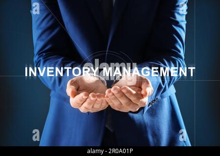 Mann berührt virtuellen Bildschirm mit Text Inventory Management auf farbigem Hintergrund Stockfoto