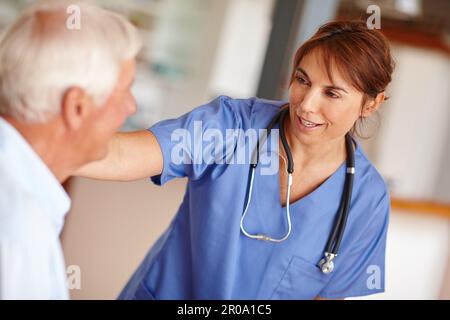 Sie ist eine nette und fürsorgliche Professionelle. Eine Krankenschwester, die nach ihrem älteren Patienten sieht. Stockfoto