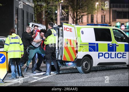 Broad Street, Birmingham, 8. Mai 2023 - die Polizei von West Midlands musste diesen Mann zu Boden ringen, nachdem er sich nach einem Vorfall in einem Nachtclub der Verhaftung widersetzte. Am Sonntagabend stiegen Reveller auf die Broad Street von Birmingham für eine königliche Afterparty ab. Die Polizei war auch bei mehreren anderen Vorfällen entlang des berüchtigten Streifens dabei, als temperiert wurde. Eine Frau wurde von einem Sanitäter in einen Krankenwagen gefahren, der einen Krankenwagen hielt. Die meisten Feiernden trugen normale Wochenend-Outfits, aber einige hielten sich immer noch an den Feierlichkeiten fest, die Union Flag Hüte und König Karl III Masken und große Ohren trugen. Der Partygänger Stockfoto