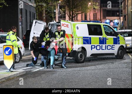 Broad Street, Birmingham, 8. Mai 2023 - die Polizei von West Midlands musste diesen Mann zu Boden ringen, nachdem er sich nach einem Vorfall in einem Nachtclub der Verhaftung widersetzte. Am Sonntagabend stiegen Reveller auf die Broad Street von Birmingham für eine königliche Afterparty ab. Die Polizei war auch bei mehreren anderen Vorfällen entlang des berüchtigten Streifens dabei, als temperiert wurde. Eine Frau wurde von einem Sanitäter in einen Krankenwagen gefahren, der einen Krankenwagen hielt. Die meisten Feiernden trugen normale Wochenend-Outfits, aber einige hielten sich immer noch an den Feierlichkeiten fest, die Union Flag Hüte und König Karl III Masken und große Ohren trugen. Der Partygänger Stockfoto