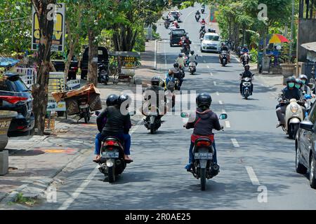 Ubud, Bali, Indonesien - 5. September 2019: Motorräder und Autos fahren in einer belebten Straße mit Straßenläden der beliebten Touristenstadt Stockfoto