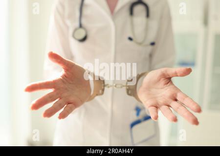 Arzt mit Stethoskop in Handschellen. Krankenschwester mit Metallhandschellen an den Händen Stockfoto