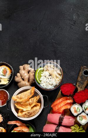 Traditionelle japanische Gerichte auf schwarzem Hintergrund, Blick von oben, Kopierbereich. Stockfoto