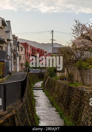 Ein kleiner Bach, der zwischen einigen Häusern in einem Wohngebiet von Kyoto, Japan, verläuft Stockfoto