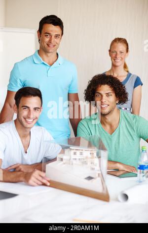 Die besten Architekten der Branche. Eine Gruppe von Architekten, die während einer Besprechung ein Gebäudemodell diskutieren. Stockfoto
