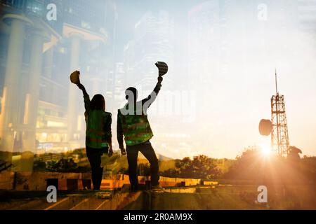 Doppelbelichtung von Ingenieuren im Bauwesen mit Schutzhelm und Bauzeichnung vor dem Hintergrund surrealer Bauwerke Stockfoto