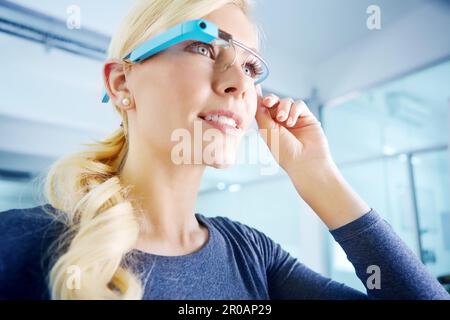Erweiterte Business-Technologie. Eine junge Frau, die in einem Büro steht und eine intelligente Brille trägt. Stockfoto