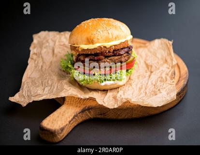 Großer leckerer Burger mit Rindfleischschnitzel auf Schwarz Stockfoto