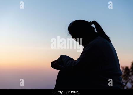 Silhouette einer Frau, die im Himmelshintergrund um Gottesverehrung betet. Christen beten zu jesus christus um Ruhe. Am Morgen kamen die Leute zu A Stockfoto