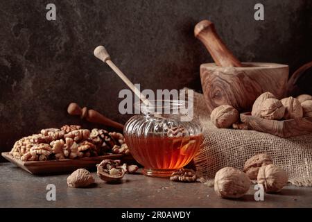 Honig und Walnüsse auf einem alten Küchentisch. Stockfoto