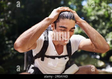 Ich fühle mich total erfrischt. Ein junger Mann, der eine Pause macht, während er im Wald wandert. Stockfoto