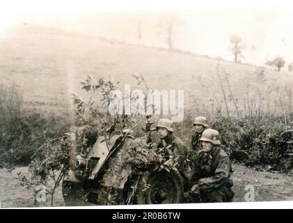 2. Weltkrieg Schwarzweißfoto Deutsche Soldaten trainieren auf einem 75mm Infanteriegewehr . Die Männer sind von der 3. SS Totenkopf Division. Sie sind in Camo Smocks gekleidet Stockfoto