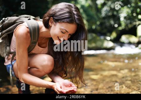 Lassen Sie den Wald Ihre Sinne füllen. Eine junge Frau hält für eine Wasserpause, während sie im Wald wandert. Stockfoto