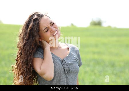 Frau mit Nackenschmerzen, die sich auf einem Feld beklagt Stockfoto